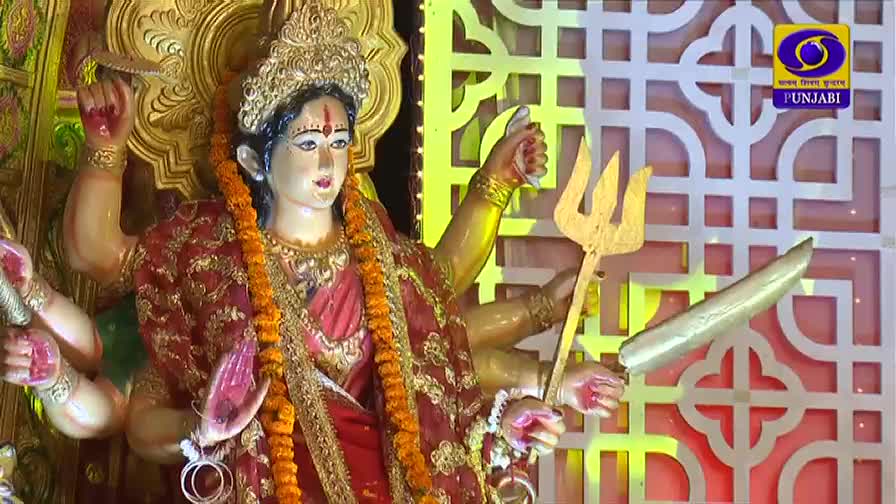 A statue of the goddess Durga, adorned with marigolds and a red sari, holds a golden trident and sword. The DD Punjabi logo is visible in the background.