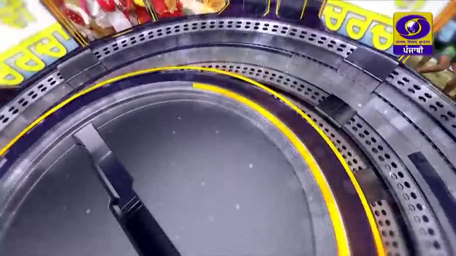 The metallic rings are spinning, revealing a glimpse of the DD Punjabi logo. A dark, pointed shape moves across the center, hinting at a countdown.