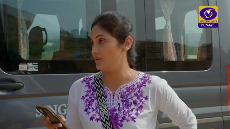 A woman stands by a vehicle, holding her phone. The DD Punjabi logo is visible on the side of the vehicle.