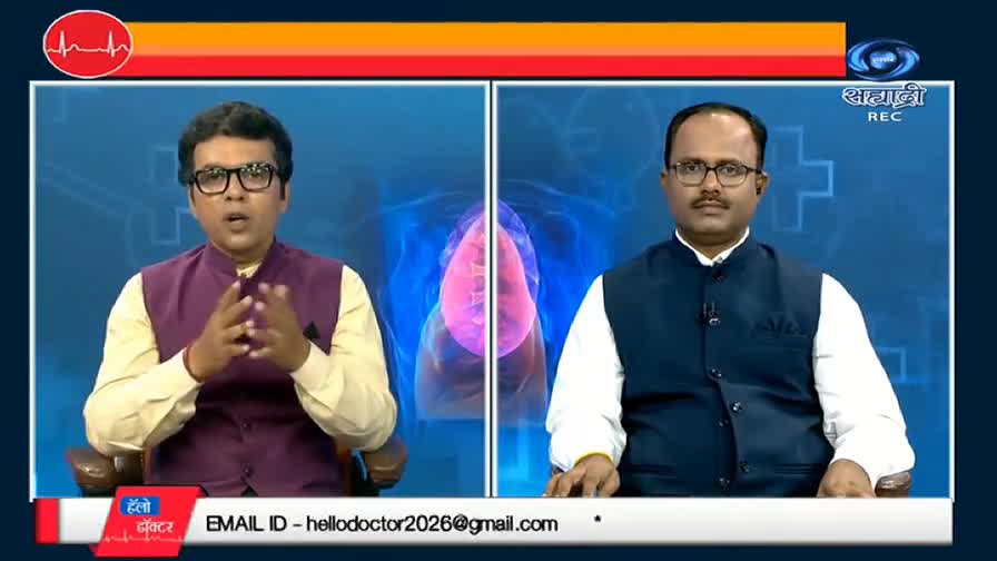 Two men in vests sit side-by-side, framed by a blue background with a lung graphic. The man on the left gestures with his hands as he speaks, while the other looks directly at the camera.
