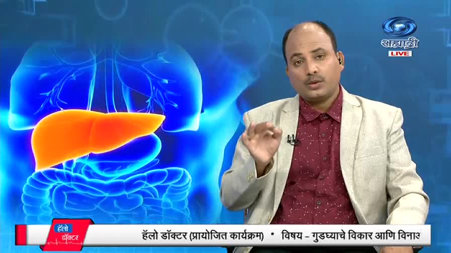 A man in a maroon shirt and beige jacket gestures with his right hand, speaking on a DD Sahyadri program. Behind him, a bright orange liver graphic floats against a blue, anatomical backdrop.
