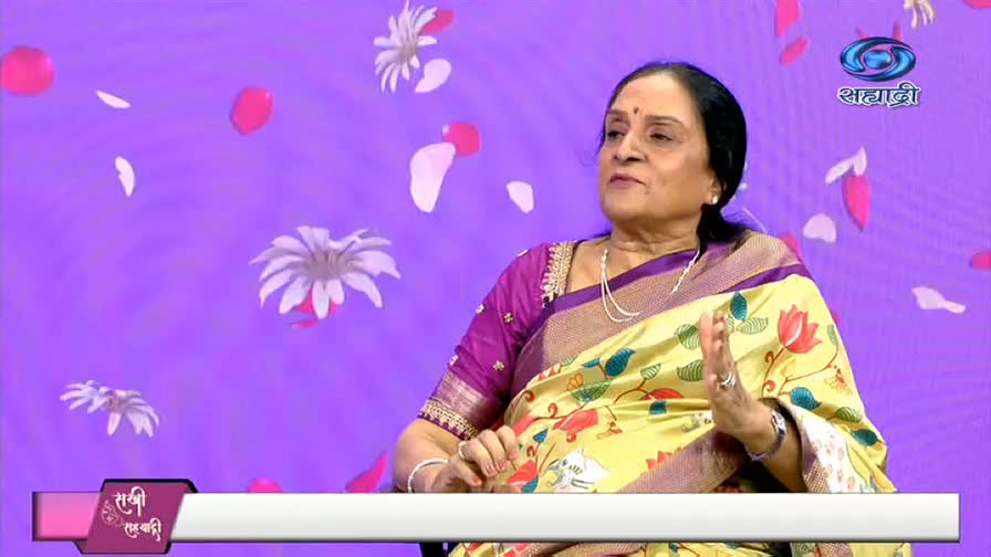 A woman in a floral sari gestures with her hands, speaking on a television program. The DD Sahyadri logo is visible in the background.
