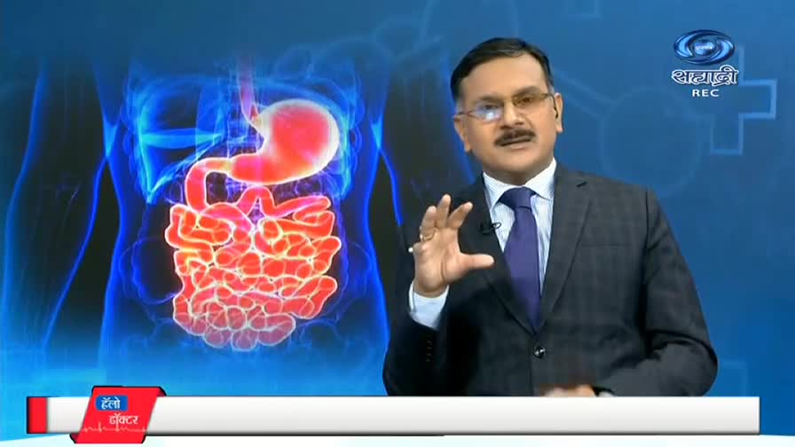 A man in a suit gestures with his hand, explaining something while standing in front of a glowing diagram of the digestive system. The DD Sahyadri logo is visible in the top right corner.
