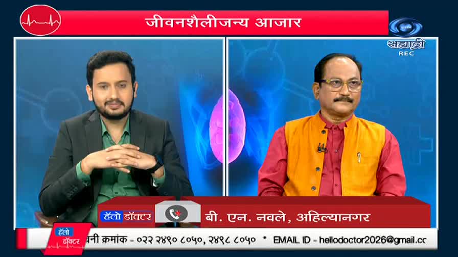 On DD Sahyadri, two men sit in a studio, each framed by a blue backdrop. The man on the right, in a red shirt and orange vest, looks directly at the camera, while the other man gestures with his hands.
