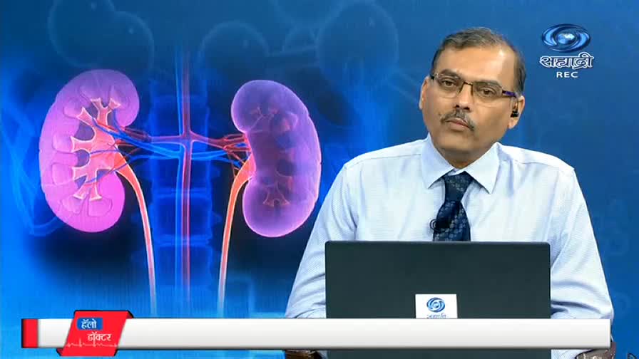 A man in glasses sits behind a laptop, facing the camera on a DD Sahyadri set. Behind him, a stylized image of kidneys glows against a blue backdrop.
