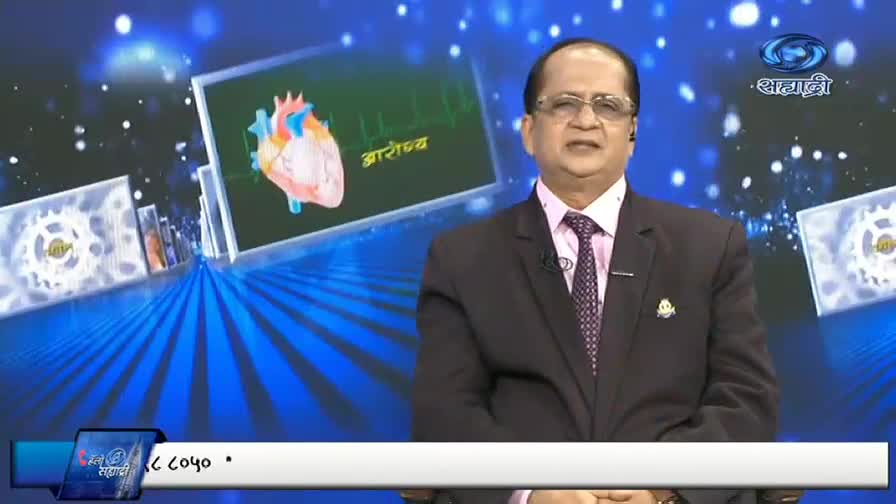 A man in a suit speaks, gesturing slightly, in front of a screen showing a diagram of a heart. The DD Sahyadri logo is visible in the corner.
