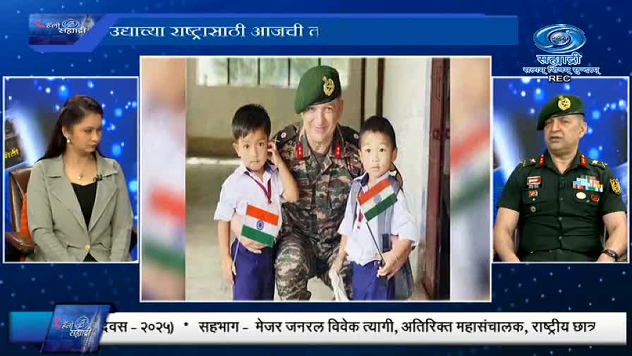 On DD Sahyadri, a news program is underway, with a panel of speakers discussing a photo of a Major General posing with two children holding Indian flags. The woman in the studio looks on, while the Major General is shown in a separate box, presumably offering his commentary.

