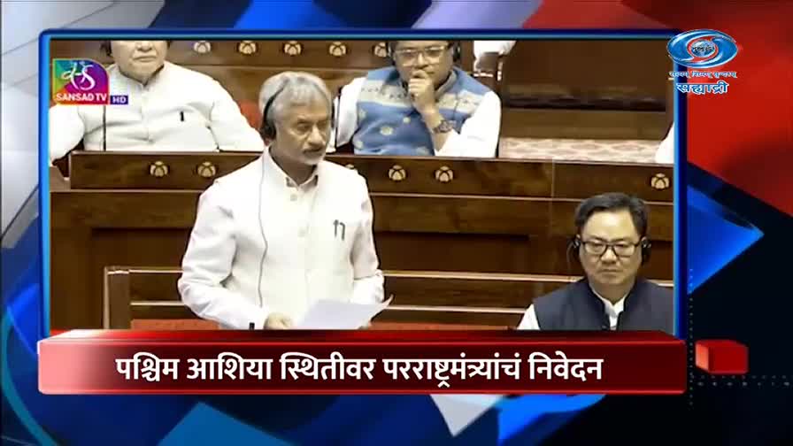 A man in a white jacket stands at a podium, speaking. Another man in a dark vest sits to his right, listening intently. The DD Sahyadri logo appears in the upper right corner.