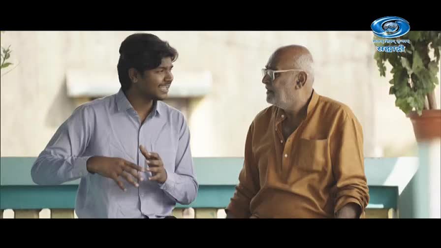 A young man in a light blue shirt gestures animatedly as he speaks to an older man in a rust-colored kurta. The DD Sahyadri logo is visible in the corner, suggesting this is a broadcast from Maharashtra.