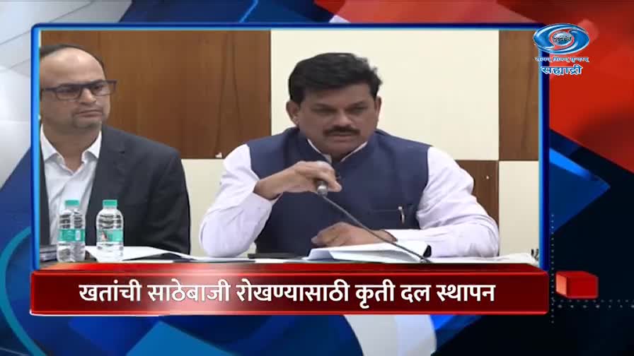 A man in a dark vest over a white shirt speaks into a microphone at a table. Beside him, another man in a dark suit and glasses watches intently. The DD Sahyadri logo is visible in the upper right corner. A man in a dark vest over a white shirt speaks into a microphone at a table. Beside him, another man in a dark suit and glasses watches intently. The DD Sahyadri logo is visible in the upper right corner.