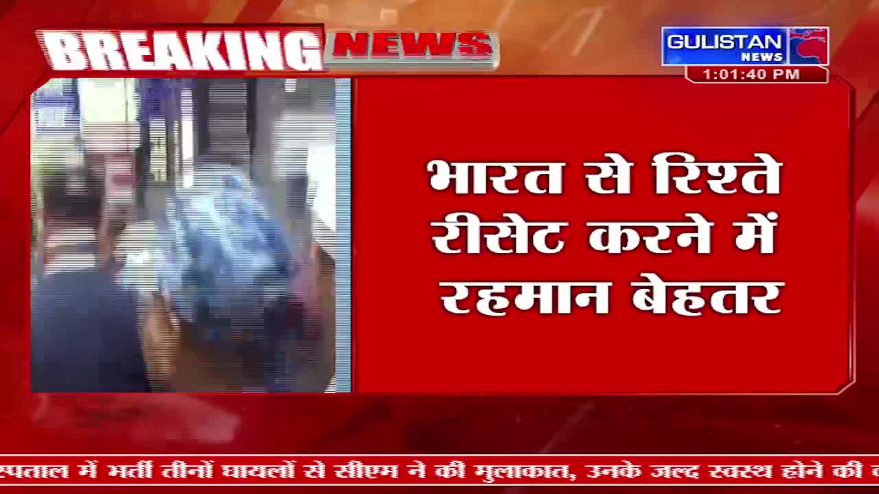 A person in a blue jacket walks past a stall. Gulistan News flashes "BREAKING NEWS" across the screen.