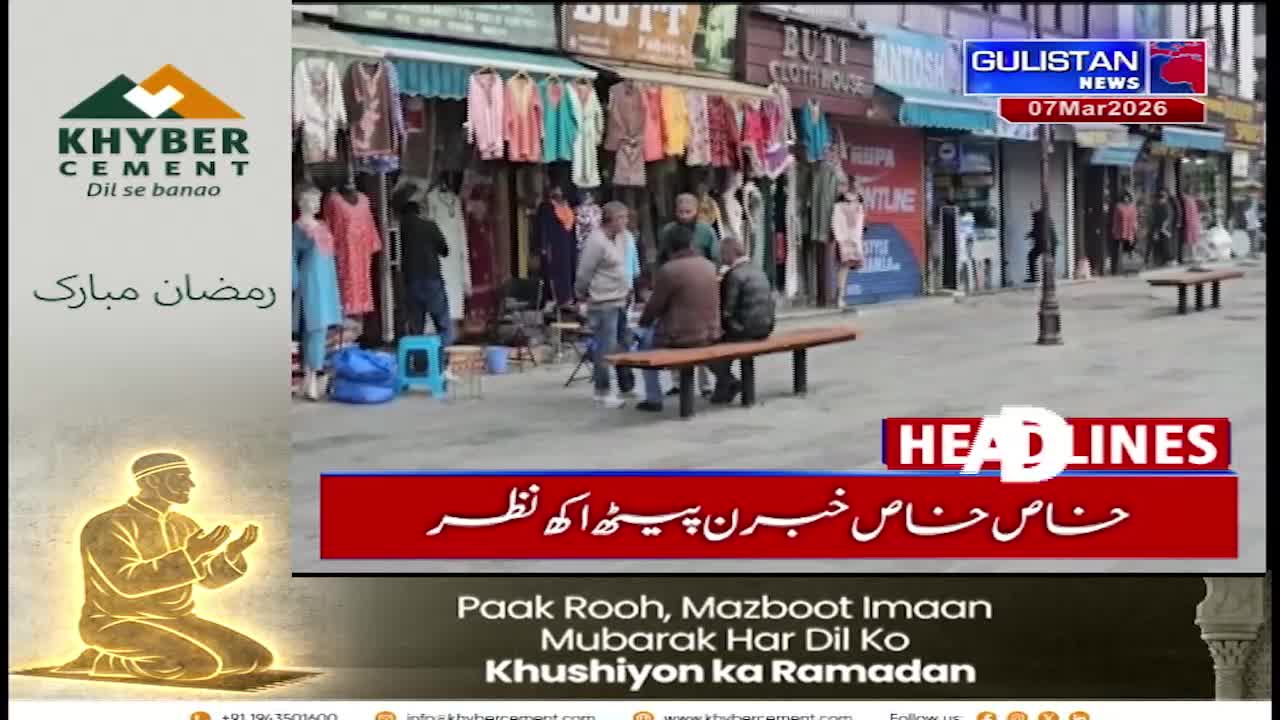 Several men gather on a street in front of shops displaying colorful clothing. A Gulistan News chyron indicates the date is March 7, 2026.