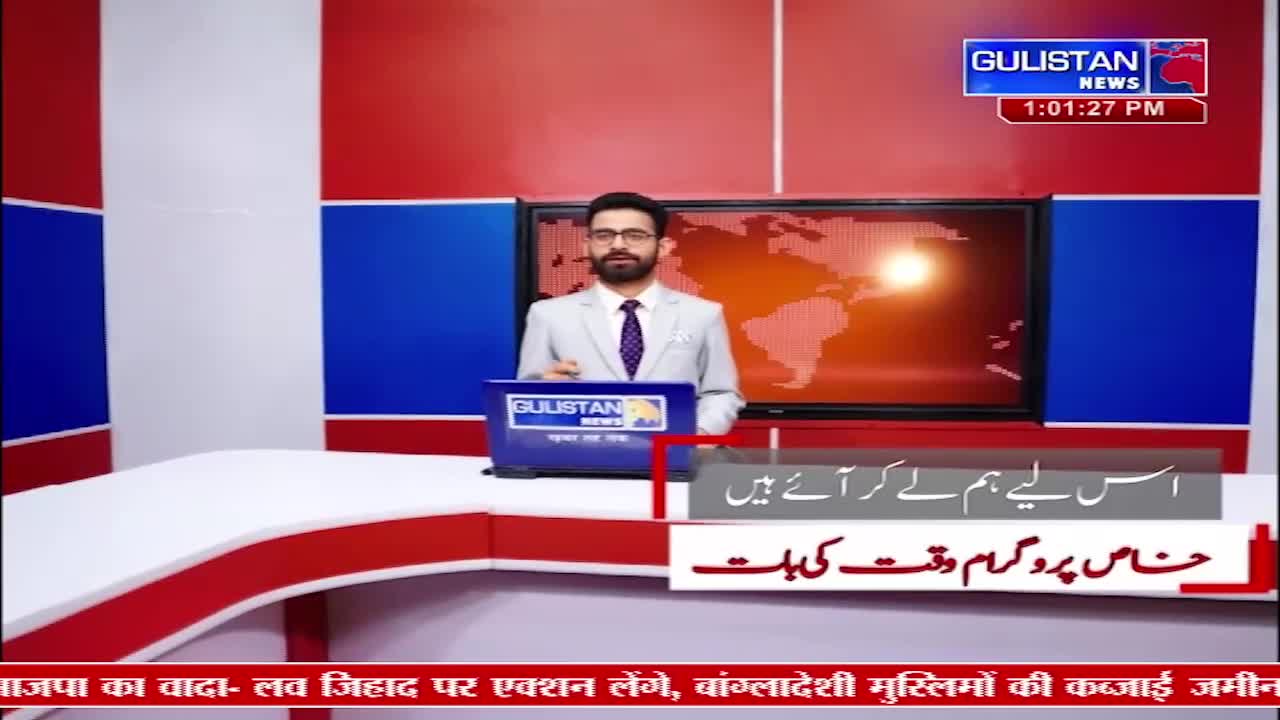 A man in a suit stands behind a desk in a studio, speaking into a microphone. A screen behind him displays a world map with a bright light. The Gulistan News logo is visible in the corner.