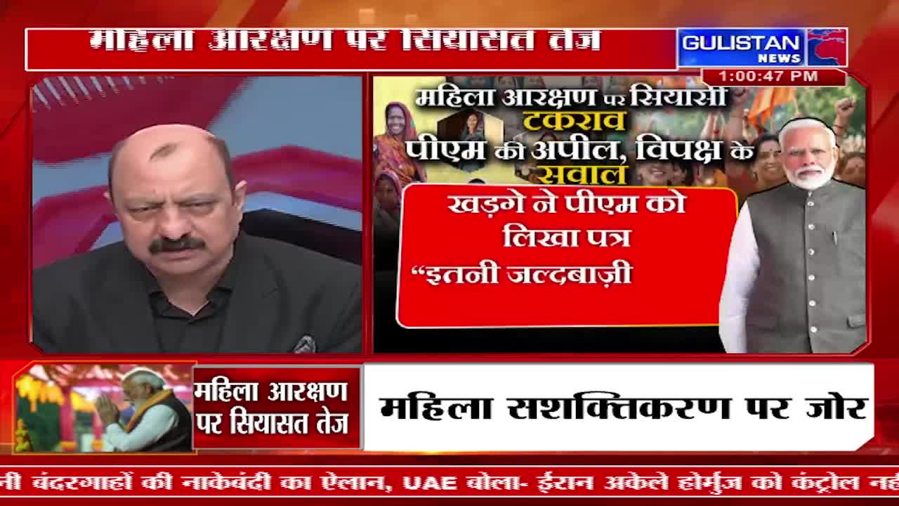 A man with a mustache sits in a suit, looking intently forward. Beside him, a news graphic displays Prime Minister Modi, surrounded by people, with text about women's reservation.