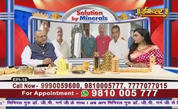 A panel of people is seated at a desk, with a display of golden objects between them. The Ishwar Bhakti TV set features a woman in a sari and a man wearing a vest, both looking at the camera.
