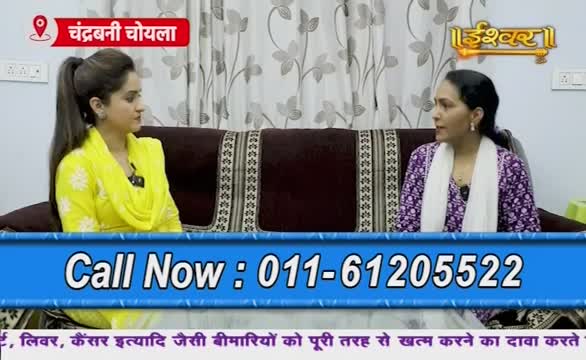 Two women are seated on a sofa, facing each other on what appears to be an Indian television show. A phone number flashes at the bottom of the screen, and the Ishwar Bhakti TV logo is visible in the corner.
