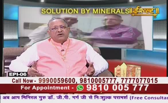 A man in a pink shirt gestures with his hands while speaking on Ishwar Bhakti TV. Behind him, a screen displays the words "Solution by Minerals" in Hindi.
