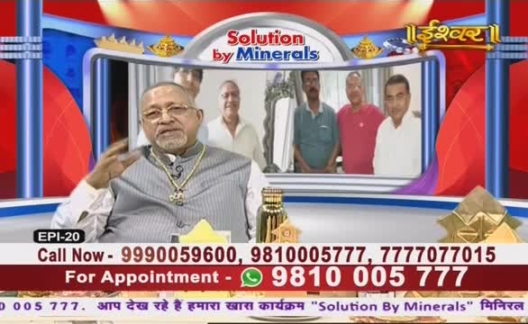 A man in a striped vest gestures with his hand, speaking on what appears to be an Ishwar Bhakti TV program in India. Behind him, a screen displays other men, and contact information scrolls at the bottom.
