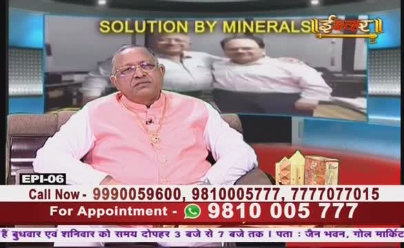 A man in a pink shirt and glasses sits in a studio, looking directly at the camera. Behind him, a screen displays a tagline about minerals, and contact information is displayed at the bottom.
