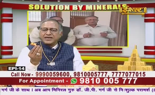 A man on Ishwar Bhakti TV in India holds up a small object, speaking animatedly. In the background, a second man stands in a room, seemingly demonstrating something.
