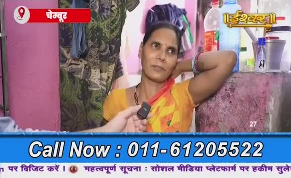 A woman in a yellow sari is speaking into a microphone; her arm rests on her head. The broadcast from Ishwar Bhakti TV is underway, with a phone number displayed on the screen.
