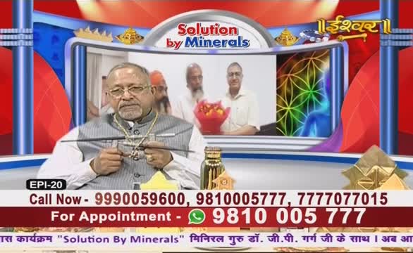 A man in a vest and glasses holds a pointer, seemingly addressing the audience on Ishwar Bhakti TV. Behind him, a screen shows two other men, while the bottom banner advertises "Solution by Minerals."
