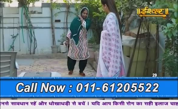 On a patio, two women stand facing each other, one in a patterned salwar kameez and a headscarf, the other in a light pink outfit. A phone number flashes on the screen as the Ishwar Bhakti TV logo sits in the corner.
