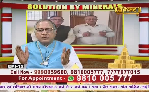 A man in a light blue vest gestures with both hands, speaking on Ishwar Bhakti TV. Behind him, two other men are visible in a framed inset, and the phone numbers for appointments are displayed below.
