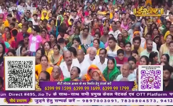 A large crowd is gathered, many looking towards a central point, possibly a stage. The broadcast from Ishwar Bhakti TV is promoting a new construction project, with contact information displayed.
