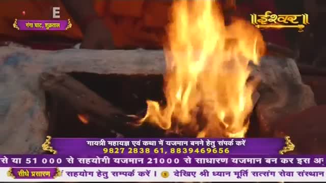 Flames leap high from a fire pit, their orange and yellow light illuminating the scene. The broadcast, from Ishwar Bhakti TV in India, shows the ritual in progress.
Flames leap high from a fire pit, their orange and yellow light illuminating the scene. The broadcast, from Ishwar Bhakti TV in India, shows the ritual in progress.