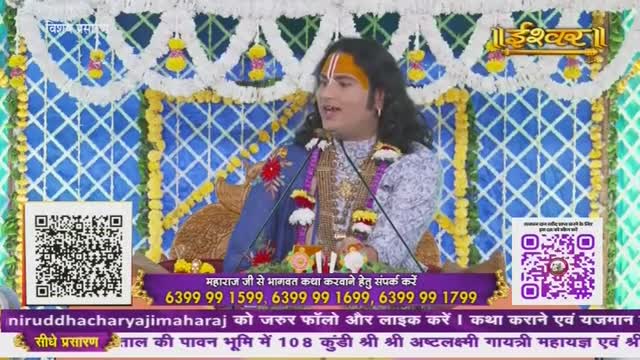 A man with a painted forehead and long hair speaks into a microphone, likely on Ishwar Bhakti TV. The background is brightly decorated with blue and white patterns, and text in Hindi scrolls at the bottom.
A man with a painted forehead and long hair speaks into a microphone, likely on Ishwar Bhakti TV. The background is brightly decorated with blue and white patterns, and text in Hindi scrolls at the bottom.