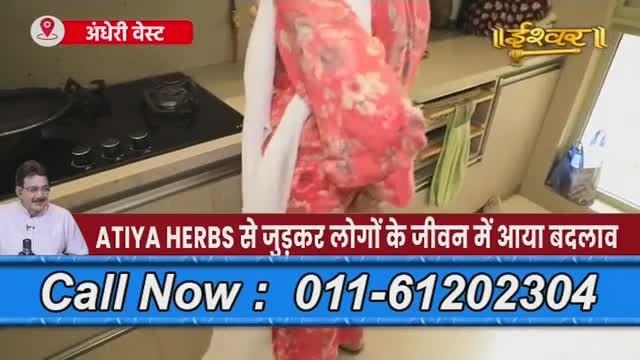 A woman in a red floral garment stands in a kitchen, while a man in a white shirt and glasses is on screen, likely from Ishwar Bhakti TV in India. The on-screen text promotes Atiya Herbs and a phone number.
A woman in a red floral garment stands in a kitchen, while a man in a white shirt and glasses is on screen, likely from Ishwar Bhakti TV in India. The on-screen text promotes Atiya Herbs and a phone number.