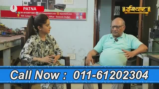 A woman in a patterned top and a man in a light green shirt sit facing each other, engaged in a conversation. The Ishwar Bhakti TV logo is visible, and a phone number is displayed at the bottom of the screen.
