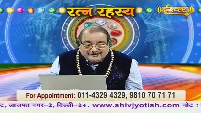 A man in a dark vest and a pearl necklace sits in front of a laptop, likely on the Ishwar Bhakti TV channel. Above him, a graphic with the words "Ratan Rahasya" and a display of gemstones is visible.
A man in a dark vest and a pearl necklace sits in front of a laptop, likely on the Ishwar Bhakti TV channel. Above him, a graphic with the words "Ratan Rahasya" and a display of gemstones is visible.