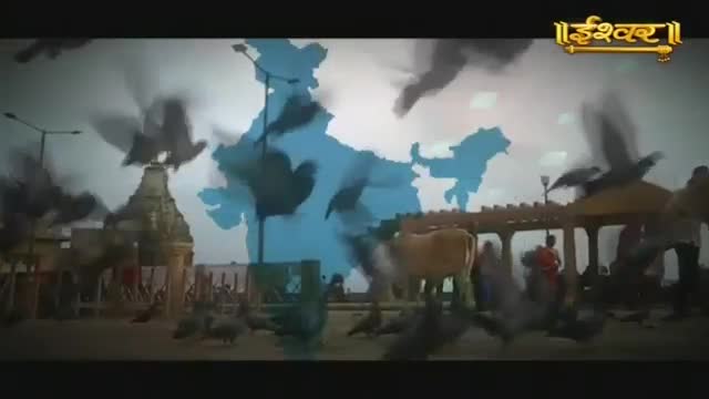 Pigeons flutter around a temple as a map of India hovers over the scene, and a cow stands calmly in the foreground. The Ishwar Bhakti TV logo is visible in the upper right corner.