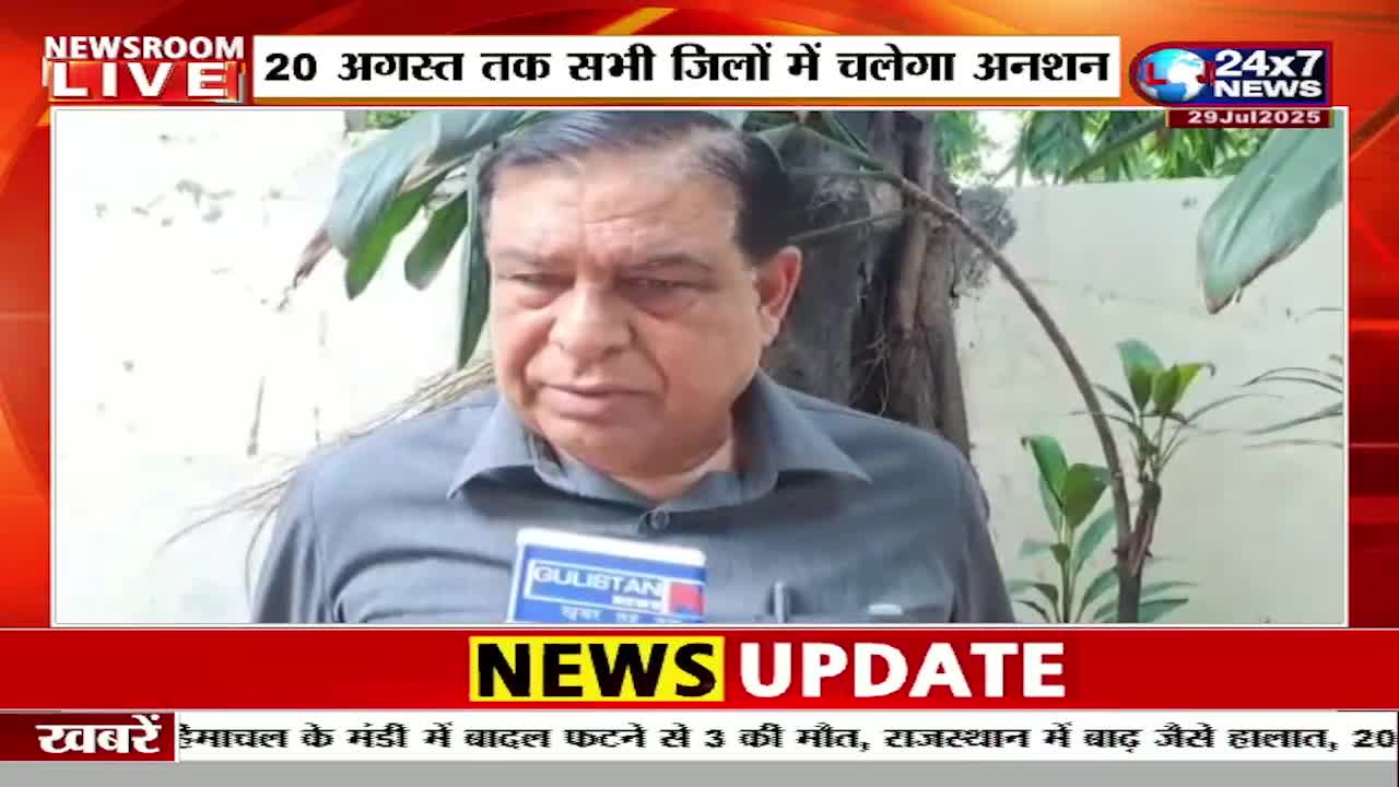 A man in a gray shirt speaks into a microphone, likely for JK 24x7 News. The screen displays a "News Update" banner, with headlines in Hindi.
