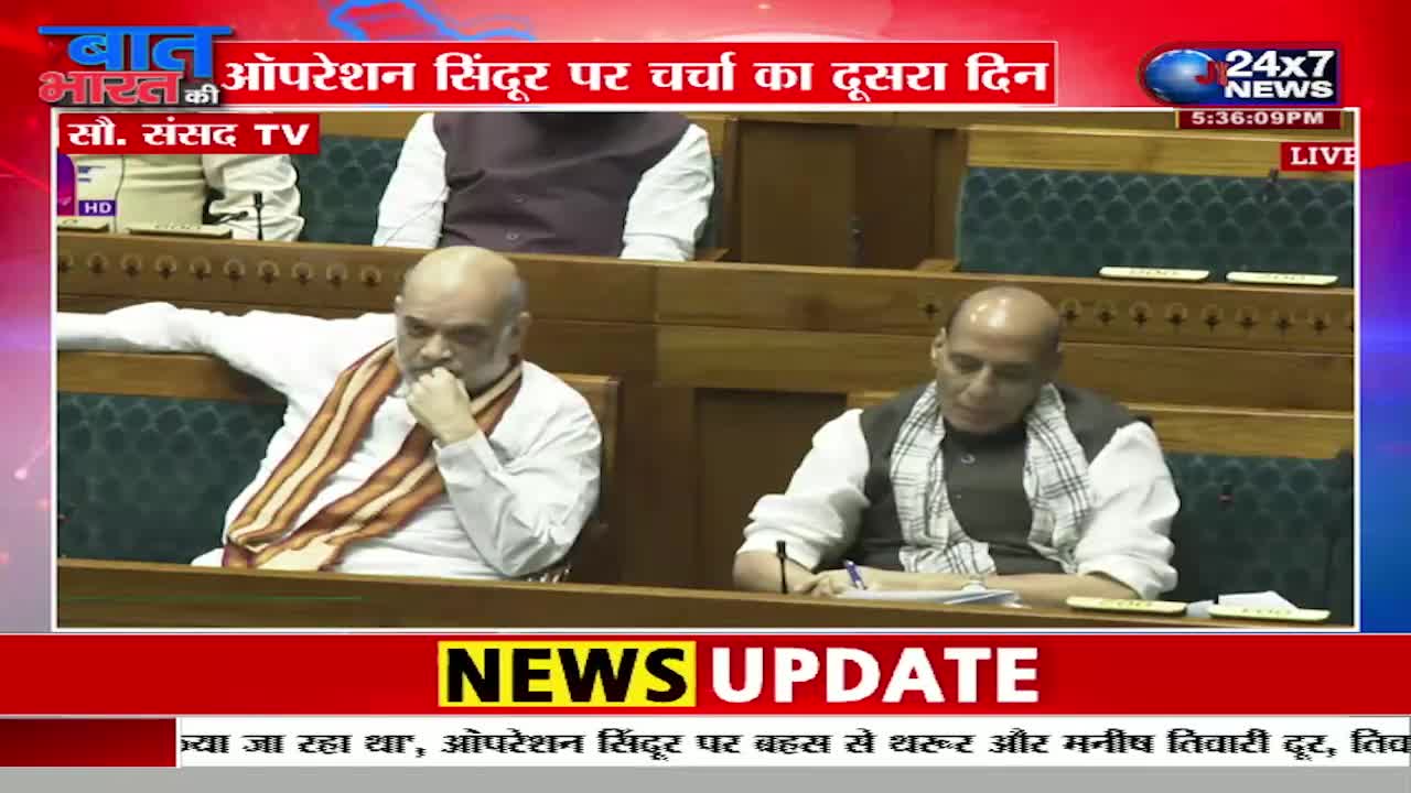 In a studio, two men sit at a table, one wearing a saffron scarf and the other writing. The JK 24x7 News logo is visible, with a headline about "Operation Sindoor" displayed across the screen.
