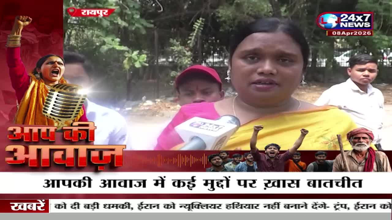 A woman speaks into a microphone, her expression earnest. Behind her, a young boy watches, and a man with a red turban stands with a stick. A woman speaks into a microphone, her expression earnest. Behind her, a young boy watches, and a man with a red turban stands with a stick.