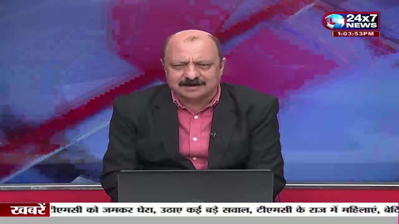 A man with a mustache, wearing a pink shirt and black jacket, speaks directly to the camera. A news ticker scrolls across the bottom of the screen, displaying headlines from JK 24x7 News. A man with a mustache, wearing a pink shirt and black jacket, speaks directly to the camera. A news ticker scrolls across the bottom of the screen, displaying headlines from JK 24x7 News.