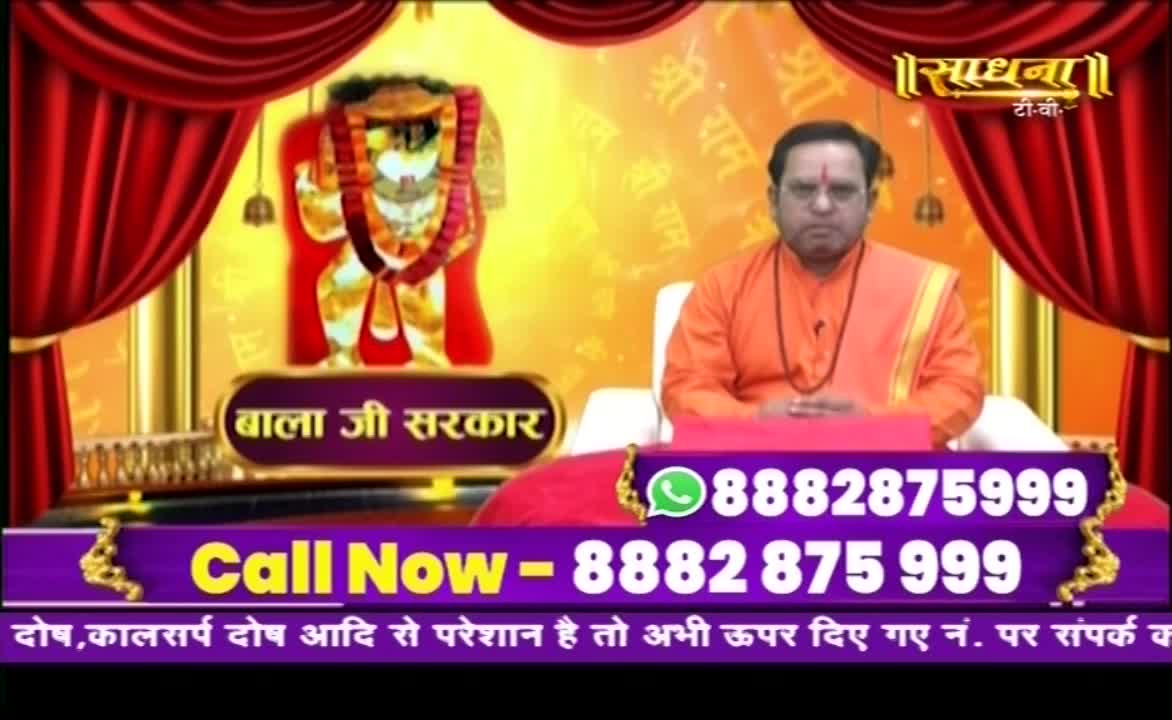 A man in orange robes sits before a backdrop of a deity and red curtains, a phone number displayed prominently below. The Sadhna TV logo sits in the upper right corner, and a call-in number is offered to those with concerns.
