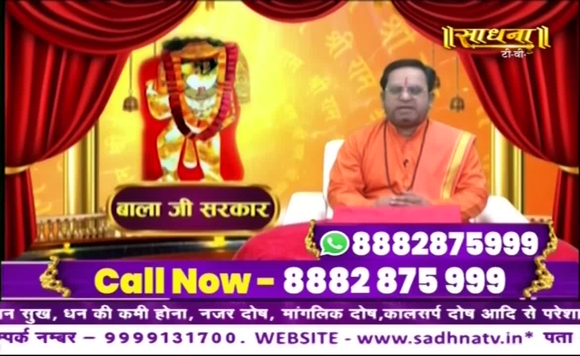A man in saffron robes sits before a backdrop featuring a deity and the Sadhna TV logo. Below, a phone number flashes, inviting viewers to call in.
