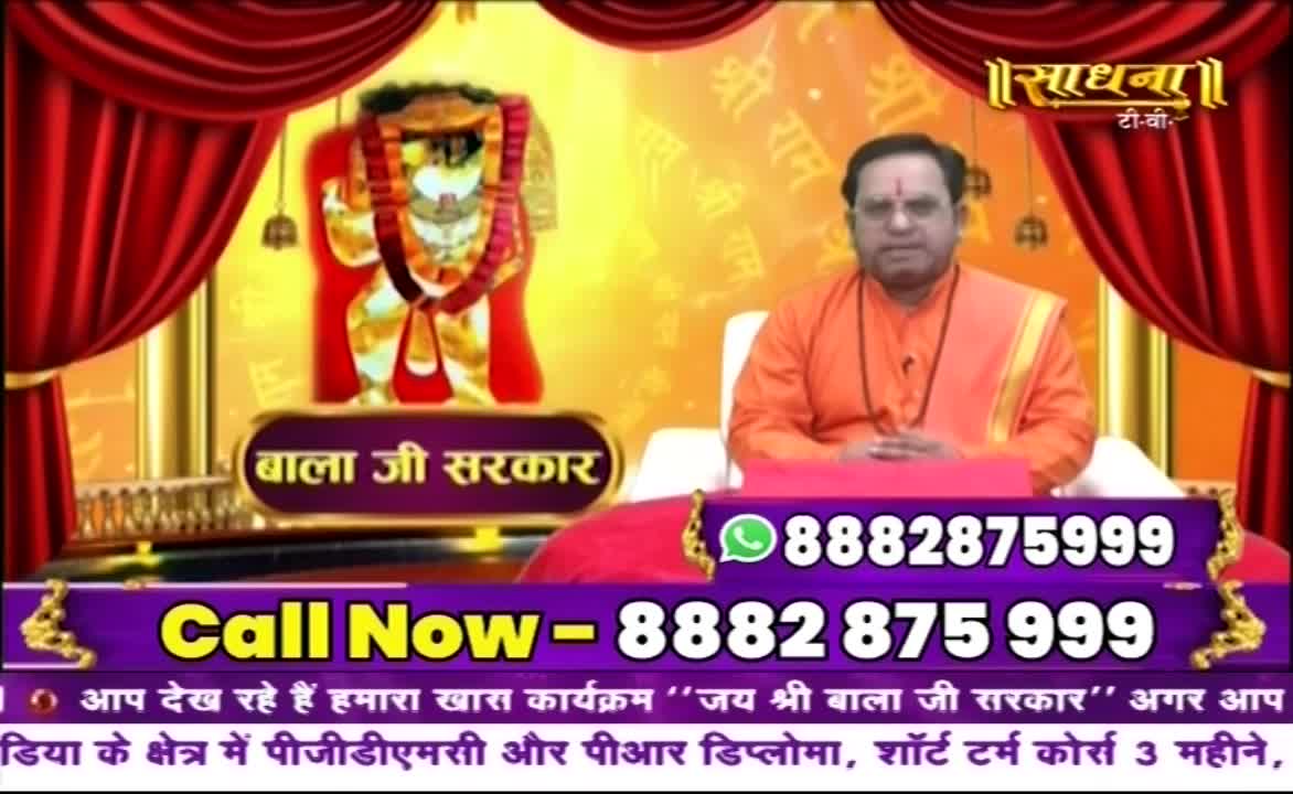 A man in saffron robes sits before a gold-colored backdrop, with an image of a deity. Below, a phone number flashes, inviting viewers to call.
