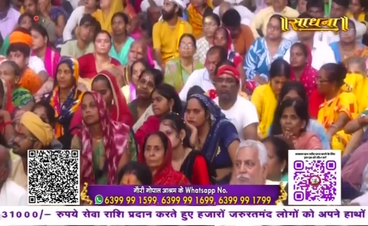 A large crowd of people, many women in colorful saris and headscarves, sits closely together. The Sadhna logo is visible at the top, and QR codes and a WhatsApp number are displayed at the bottom.
