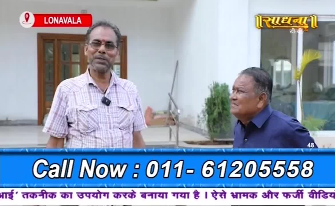 Two men stand outside, likely in Lonavala, India, with a building behind them. They're on a Sadhna TV show, as indicated by the logo, and a phone number flashes on the screen below them.
