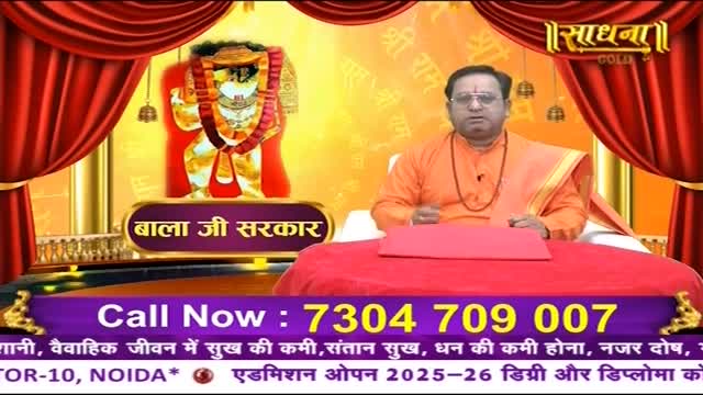 A man in orange robes gestures while seated at a red table, a golden image of a deity behind him. The Sadhna Gold logo and a phone number are prominently displayed below.
