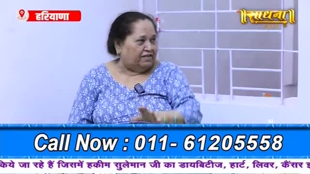 A woman in a patterned blue top gestures with her hands as she speaks. Beneath her, a phone number flashes on a blue banner, inviting viewers to call.
