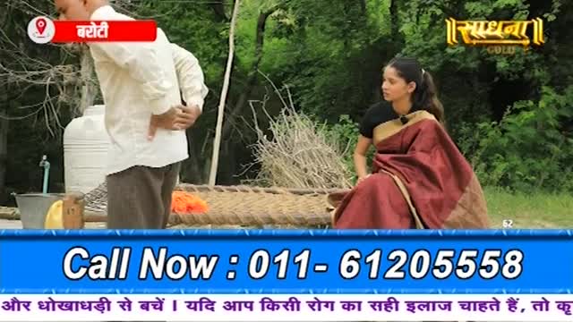 A man in a white shirt clutches his lower back, his gaze directed downwards. A woman in a maroon sari sits nearby, her attention also averted.