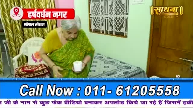 An elderly woman in a green sari holds a white roll of something, looking down at it. A red and white banner above her reads "Harshvardhan Nagar, Bhopal Special."