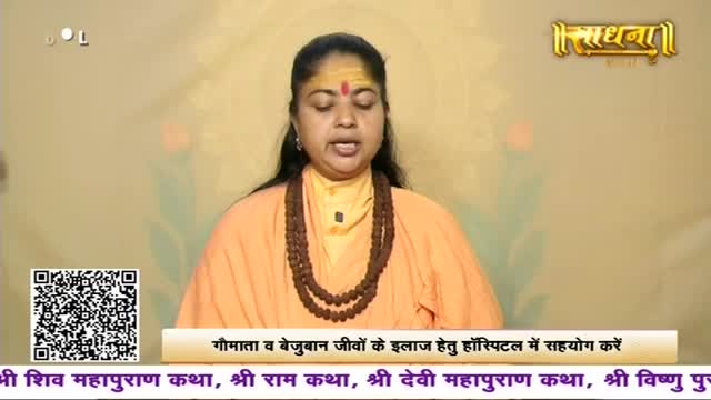 A woman in an orange robe speaks, her eyes closed, a mala draped around her neck. A banner below her displays text in Hindi, and a QR code sits in the lower left corner.