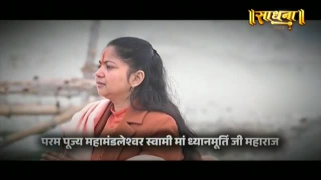 A woman with a red mark on her forehead gazes into the distance, her orange robe draped over her shoulders. The Sadhna logo appears in the upper right corner.